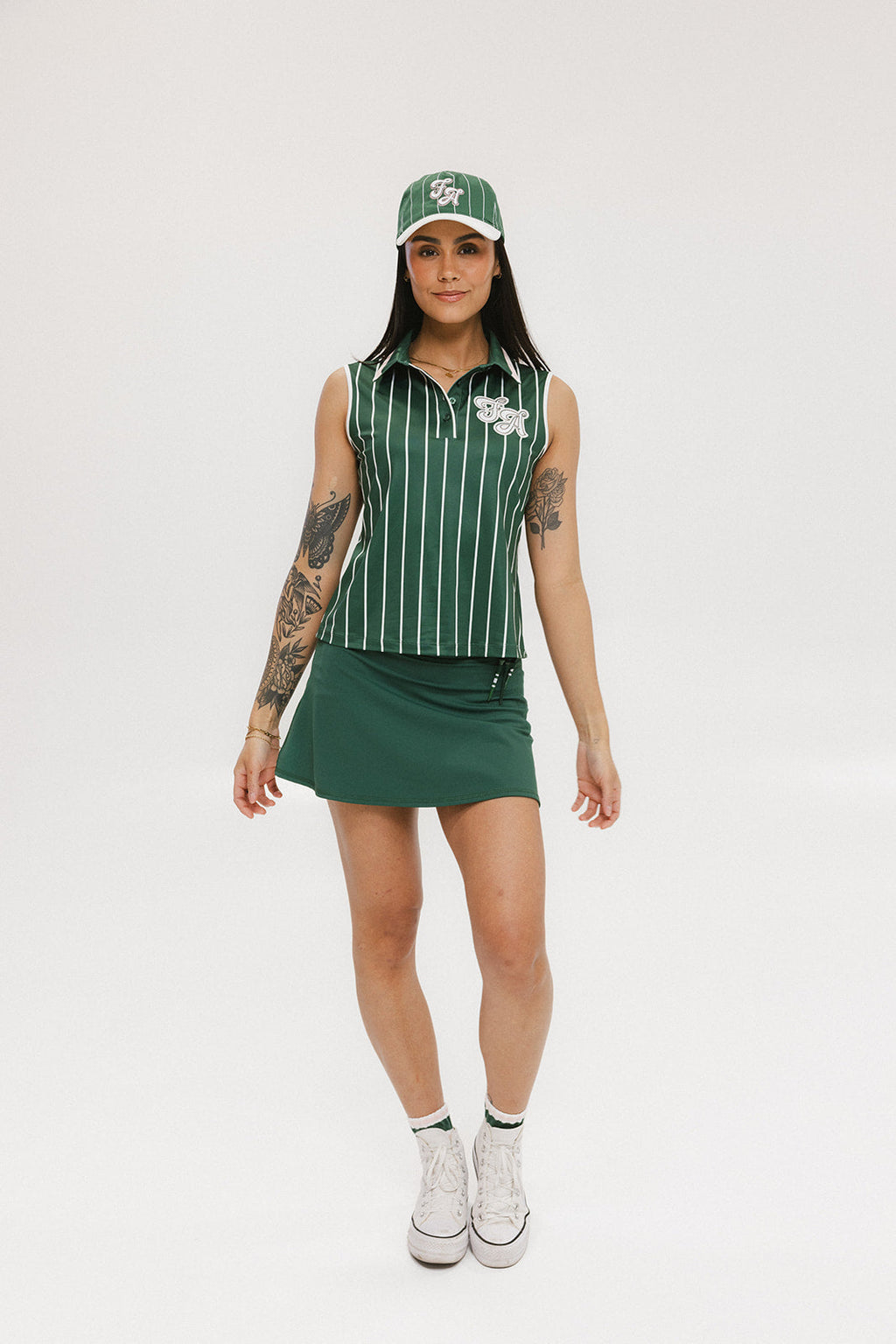 A green baseball cap with pinstripe detailing and an embroidered logo worn by a model against a white background.