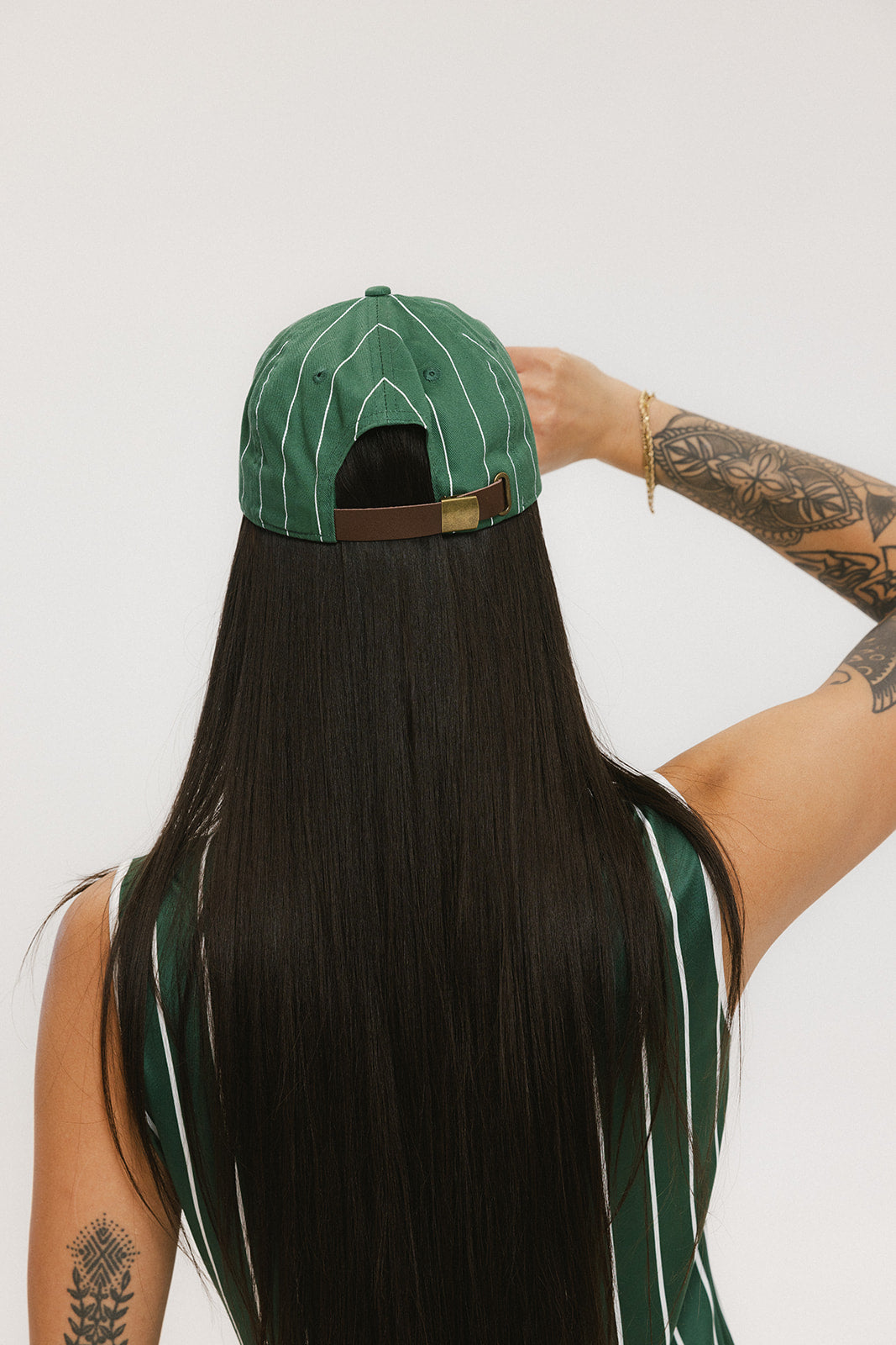 A person viewed from behind wearing a green striped hat with a brown band.