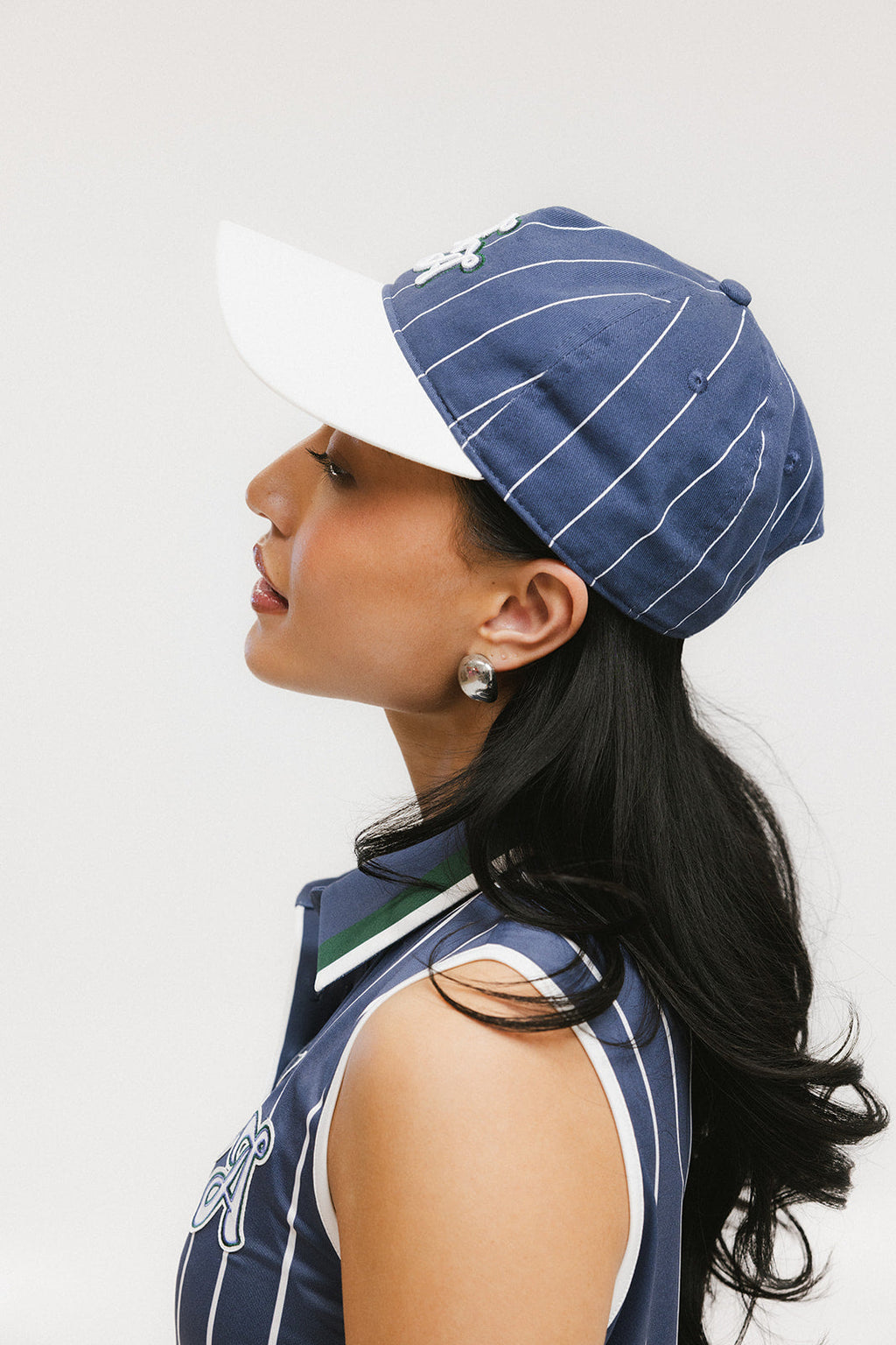 A model wearing a blue and white striped baseball cap with an embroidered logo