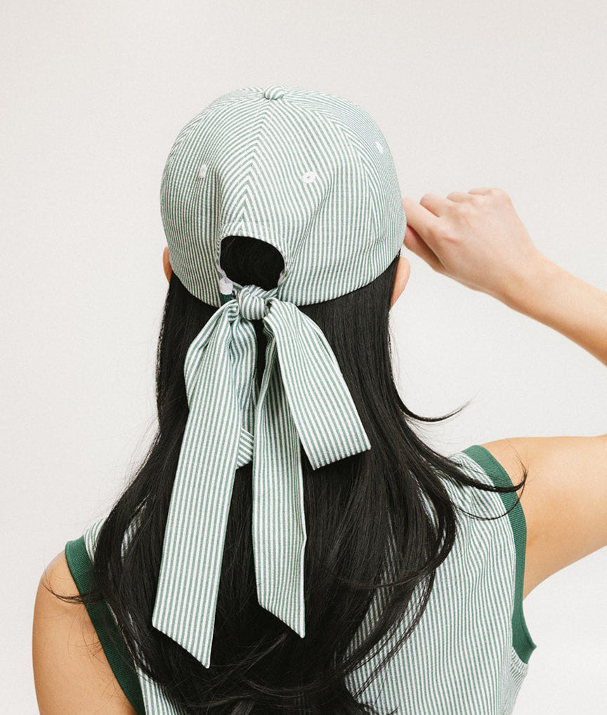 A person viewed from the back wearing a green seersucker hat with a bow