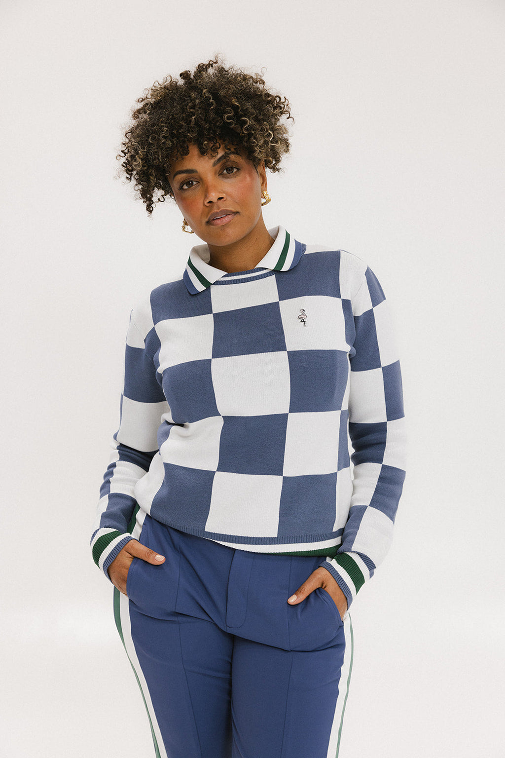A woman wearing a sleeveless, checkered indigo and white sweater with a mock neck.