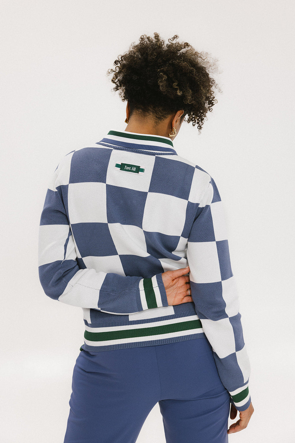 A woman wearing a sleeveless, checkered indigo and white sweater with a mock neck.