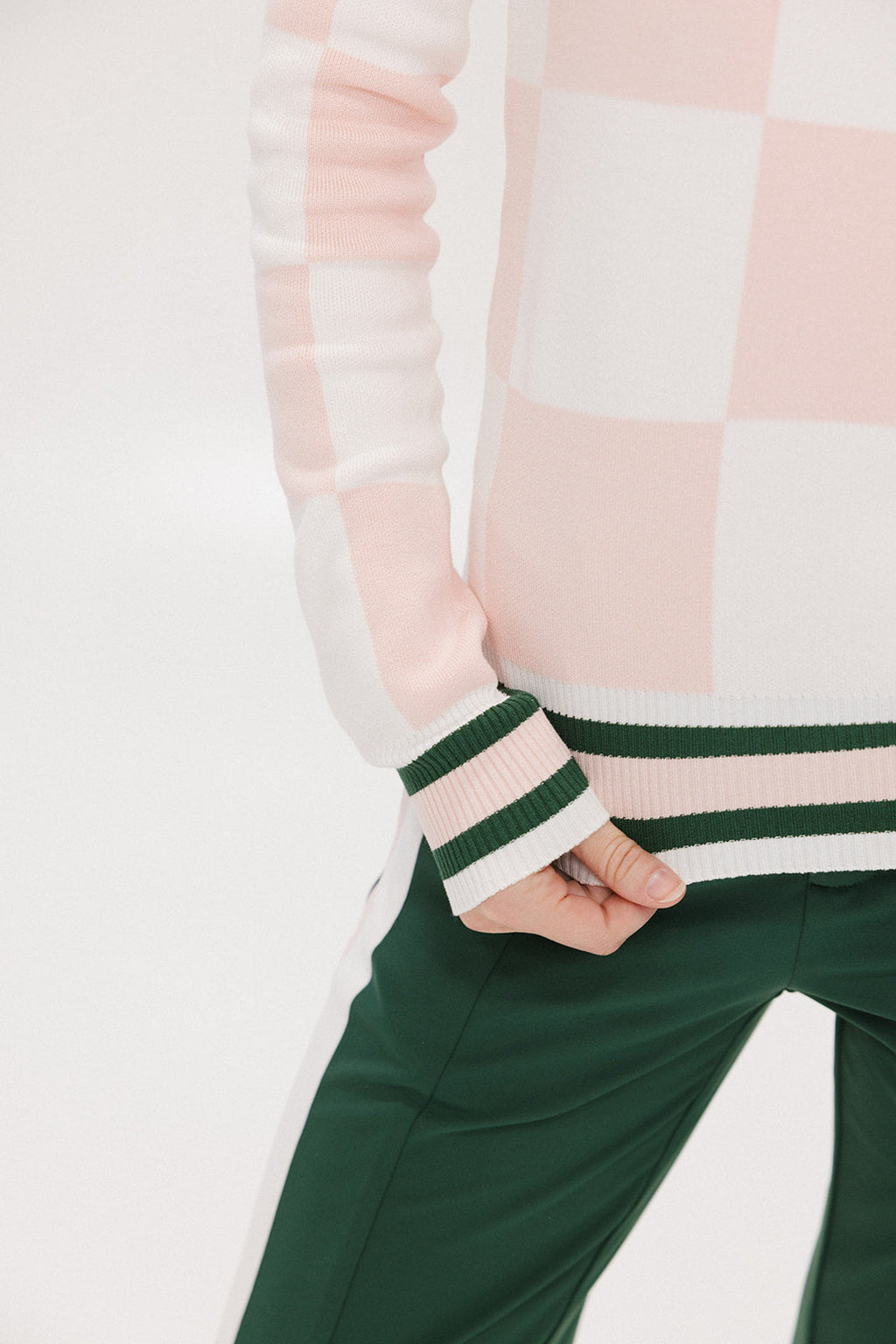 A woman wearing a pink and white checkered intarsia knit sleeveless sweater with a rounded neck.