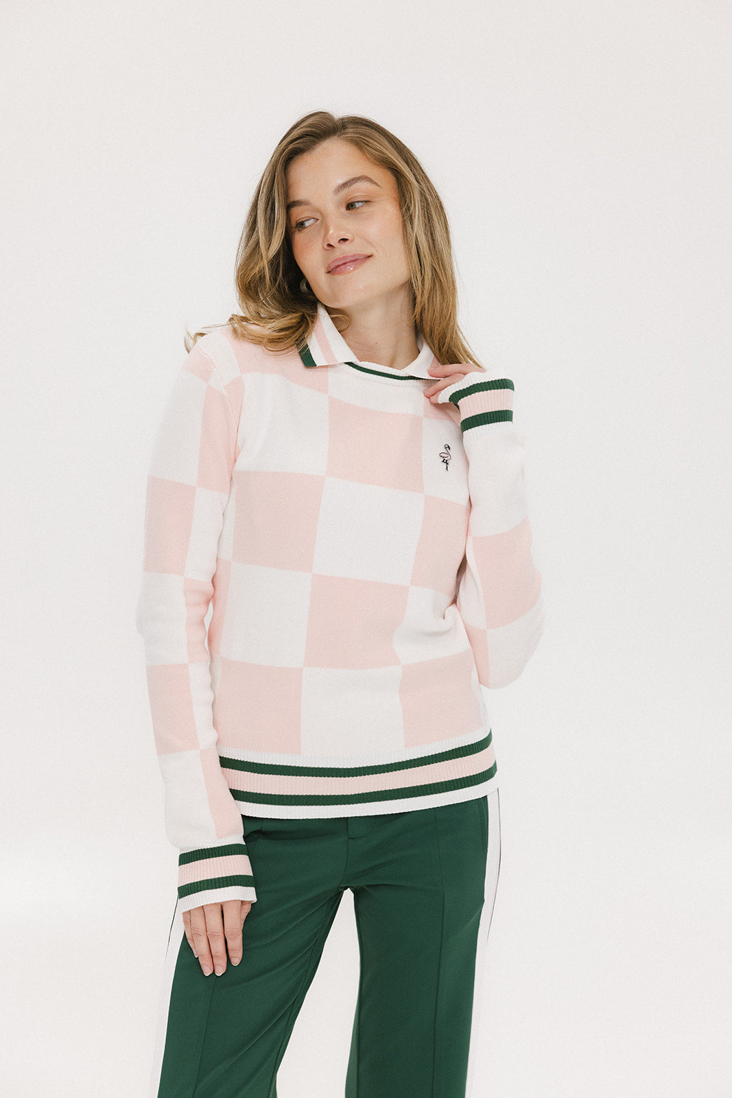 A woman wearing a pink and white checkered intarsia knit sleeveless sweater with a mock neck.