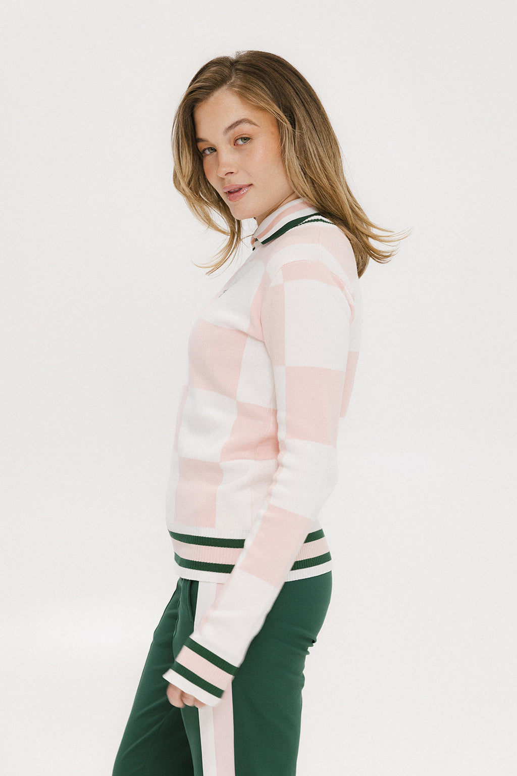 A woman wearing a pink and white checkered intarsia knit sleeveless sweater with a rounded neck.