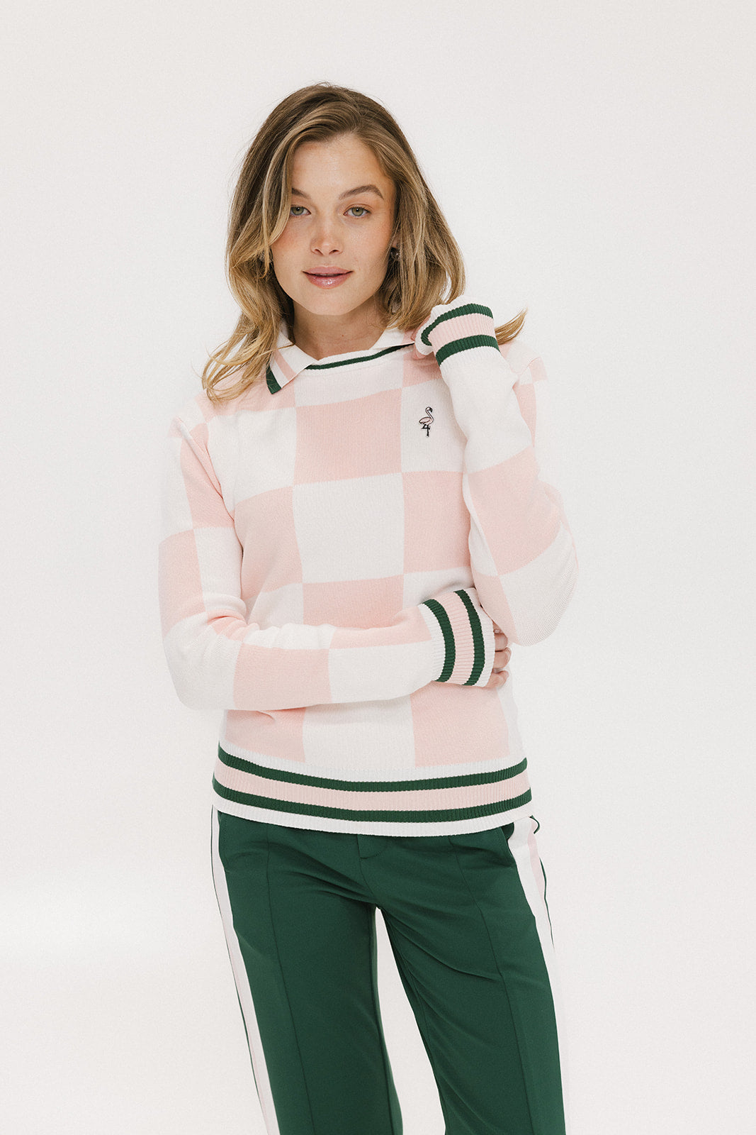 A woman wearing a pink and white checkered intarsia knit sleeveless sweater with a rounded neck.