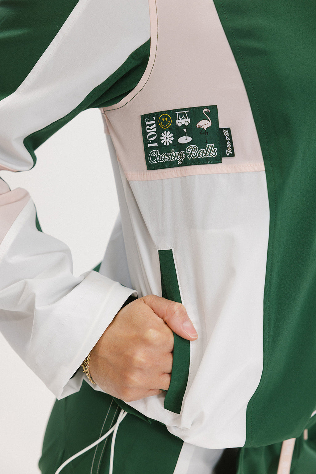 Close-up of a green and pink warm-up jacket with a logo on the sleeve.