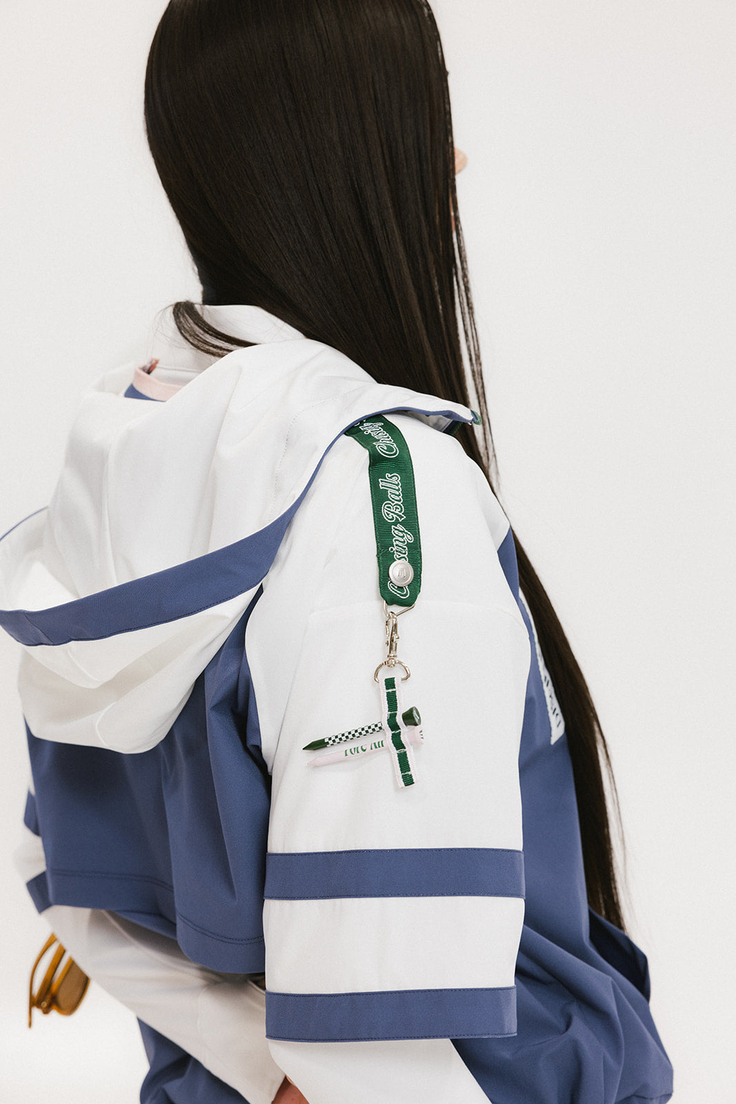 A woman wearing a blue and white hoodie with a half-zip feature and a kangaroo pocket, paired with a white skirt.