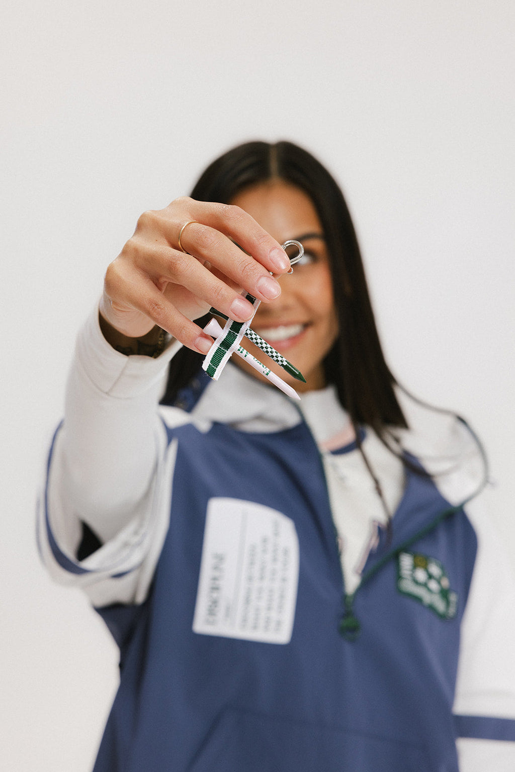 A woman wearing a blue and white hoodie with a half-zip feature and a kangaroo pocket, holding an included tee holder.