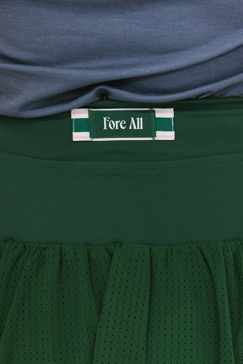 A Fore All tag on the back of a green angel skirt that features a mesh back.