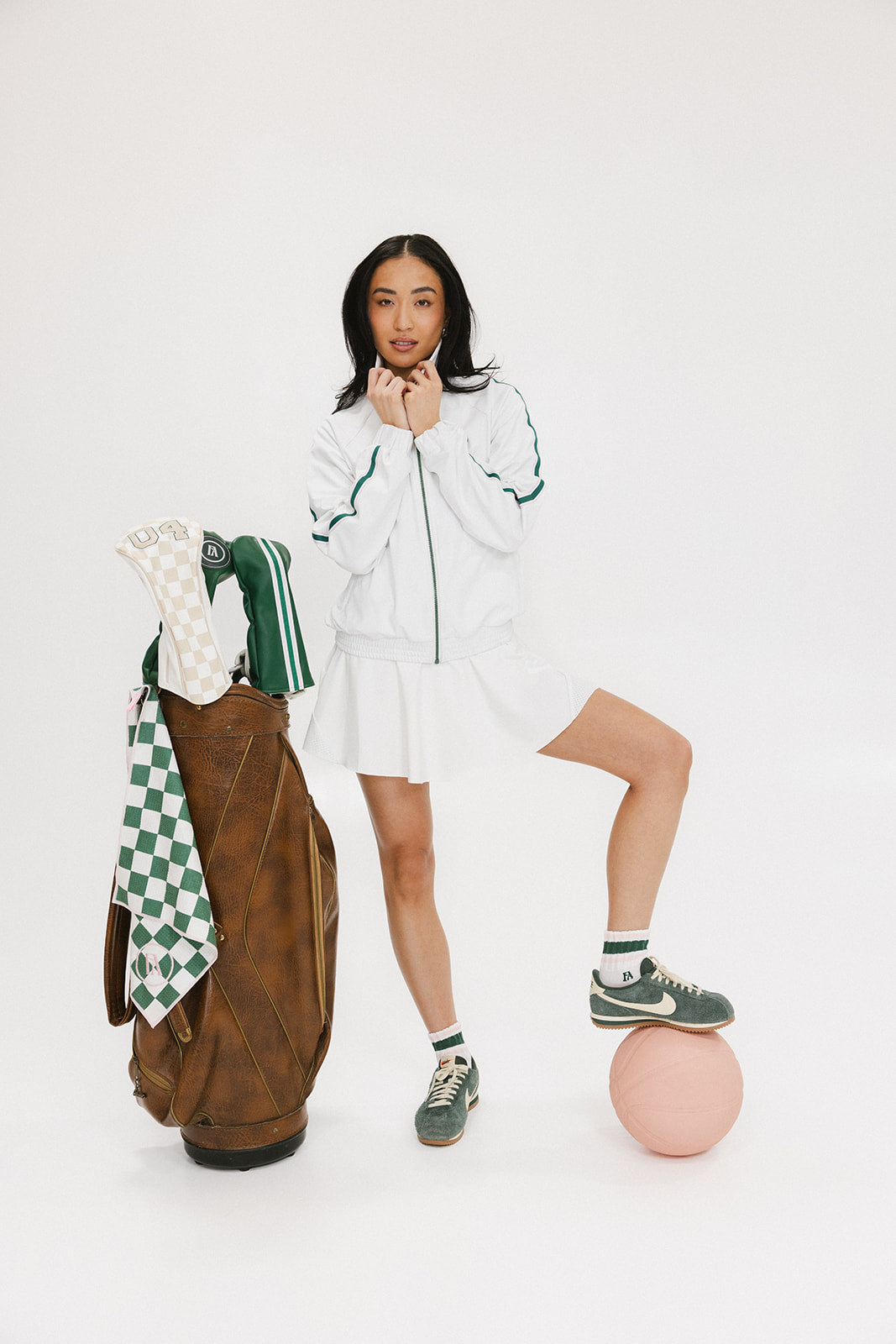 A person wearing a white angel skirt with a white top, posing with a brown bag and a pink ball at their feet.
