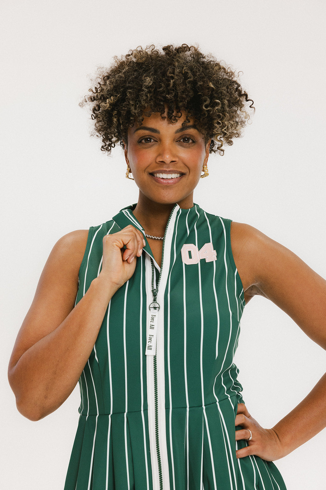 A woman wearing a sleeveless, v-neck, pinstripe green and white dress with a belt.