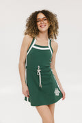 A woman wearing a green sleeveless dress with white accents and a round drawstring cord.