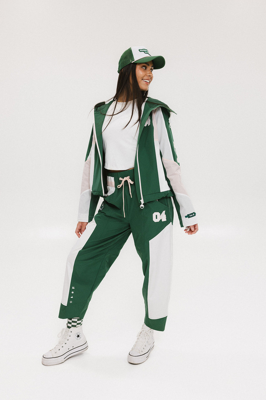 A pair of color-blocked green and white warm-up pants with a pink stripe, featuring a flat drawstring waistband and deep front pockets, branded with the 'Fore All' detail on the back and an FA icon on the inner calf.