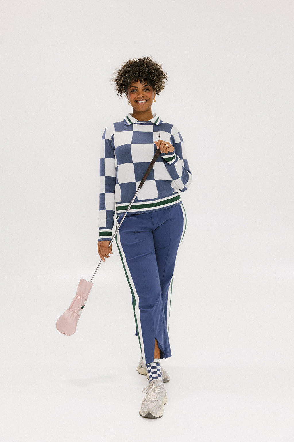 A person wearing the Simone Pant in blue with white stripes on the side, featuring princess seams down the leg and a slit at the hem. The person is also wearing a checkered blue and white top and white sneakers.
