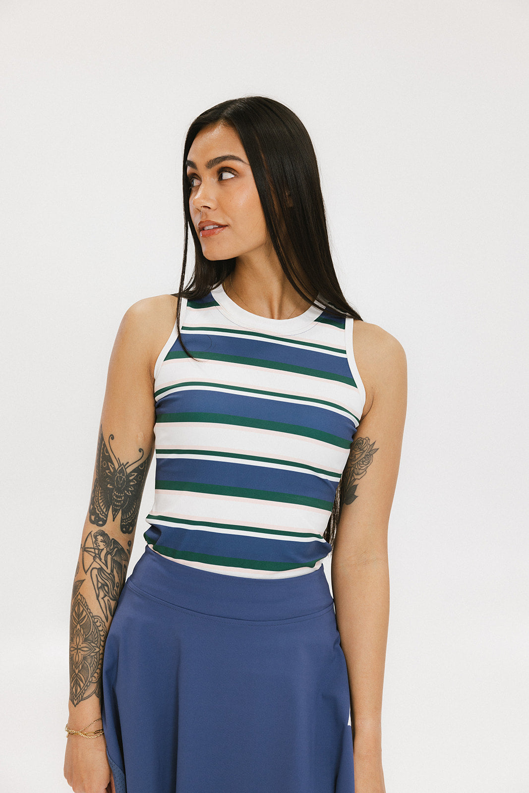 A woman wearing a sleeveless tank top with a striped pattern in blue and white colors, paired with a solid blue skirt.